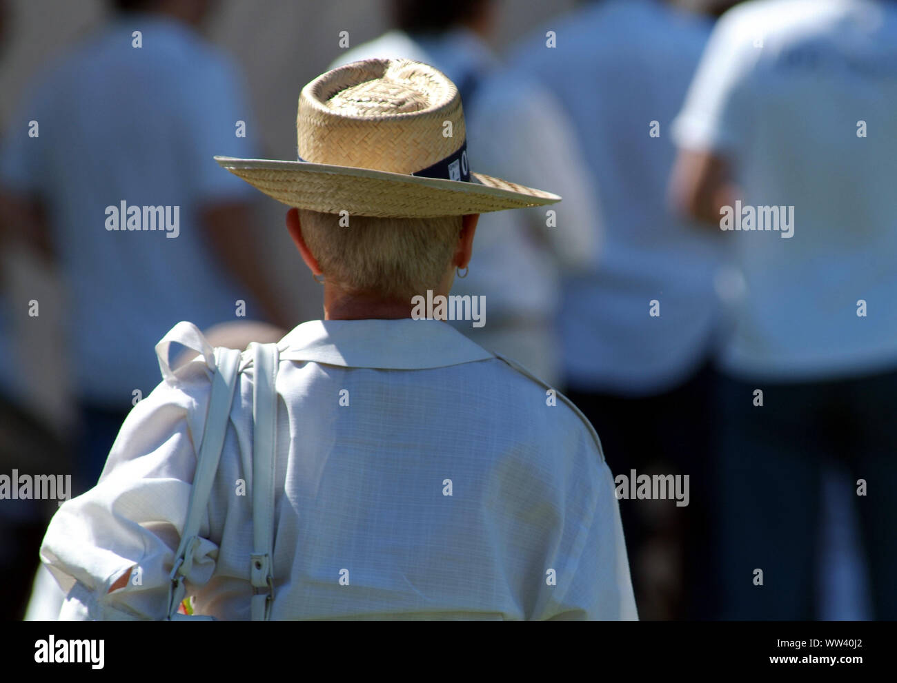 Un adulto donne lato posteriore con una camicia bianca e la borsetta e un cappello di paglia, camminare da solo con un atteggiamento elegante Foto Stock