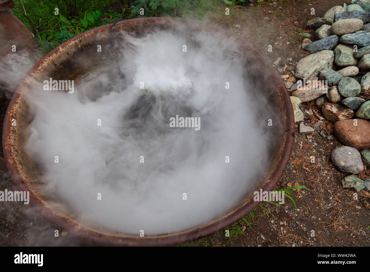 Una grande pentola o padella a fuoco durante la preparazione di una pozione o un pasto, evaporazione di una grande quantità di vapore mentre acqua bollente. Mistico culto occulto di t Foto Stock