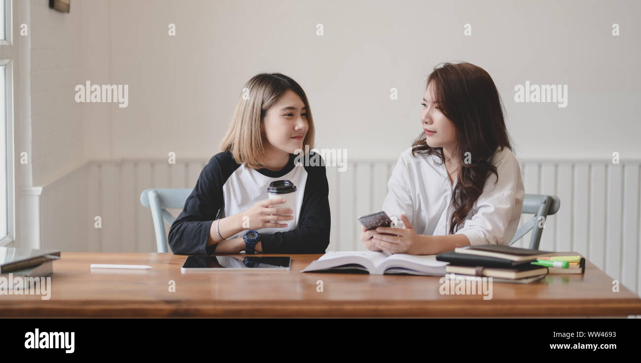 Due adorabili giovani femmine chiacchierare insieme mentre si lavora sul loro progetto in camera confortevole Foto Stock