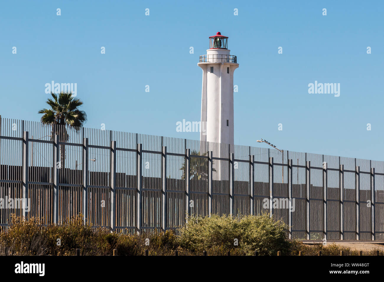 Recinzione di confine che separa San Diego in California e Tijuana, Messico, con El Faro de Tijuana faro sul lato del Messico. Foto Stock