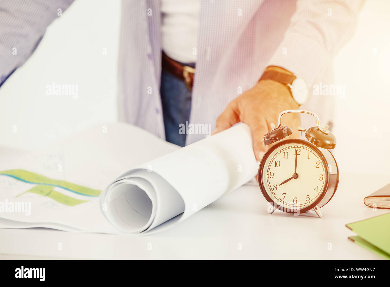 Ingegnere di lavoro volte alla ricerca di clock piano di costruzione sulla scrivania la mattina giorno Foto Stock