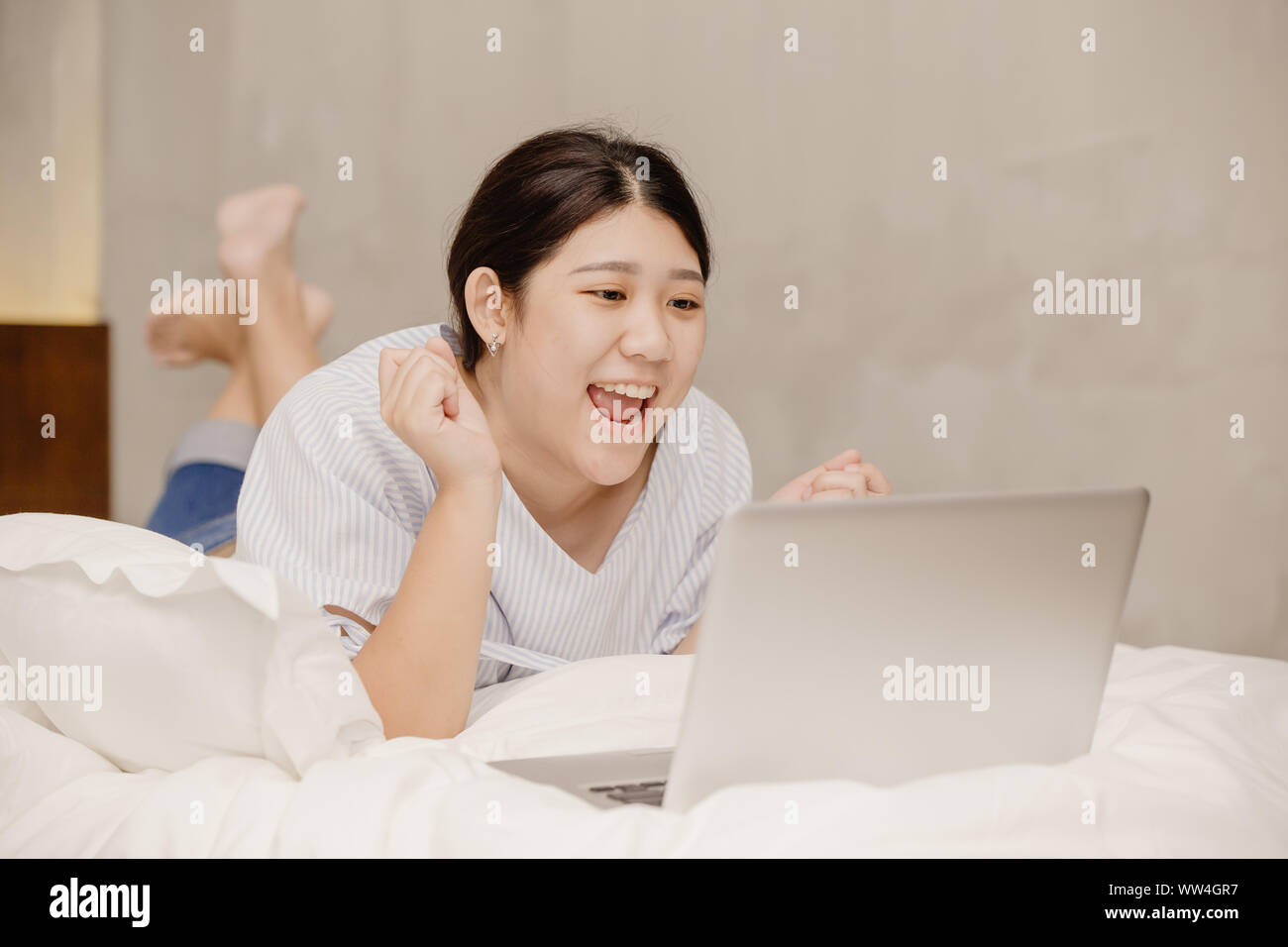 Lazy girl teen felice eccitante buone notizie da computer laptop giaceva sul letto di lavoro a casa Foto Stock