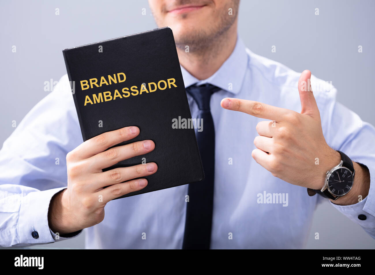 Uomo con Libro con Ambasciatore del marchio testo e puntamento Foto Stock