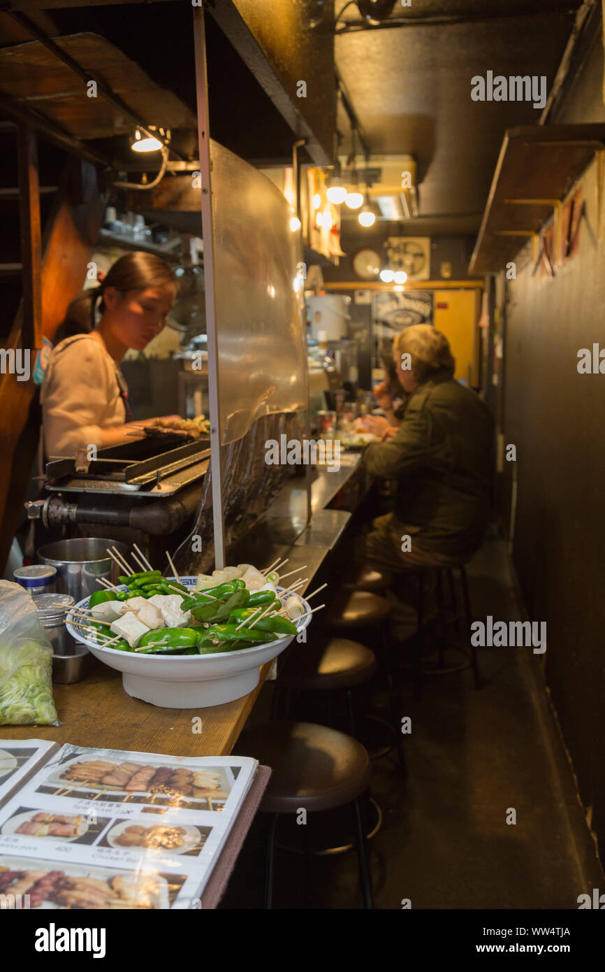 Shinjuku, Tokyo, Giappone. In questi ultimi giorni, Izakaya è diventato sempre più popolare tra i visitatori stranieri, con un menù in inglese, proprietario prepara il cibo per loro. Foto Stock