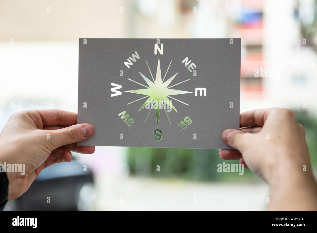 Mani tenendo la carta con ritaglio all'esterno della bussola Foto Stock