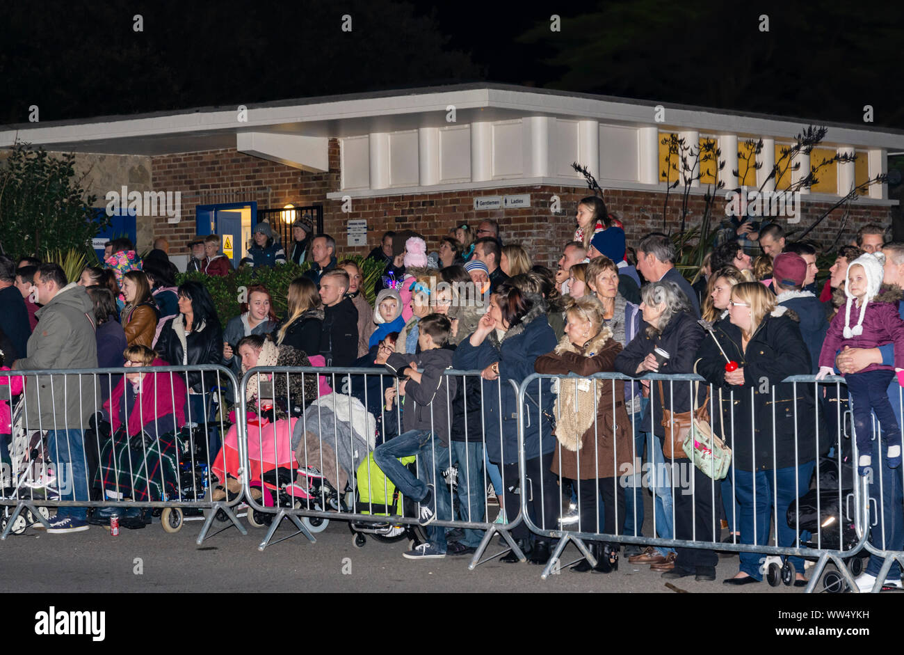 La folla di persone in piedi in attesa dietro barriere guardando una processione mentre a Guy Fawkes evento in Inghilterra, Regno Unito. Foto Stock