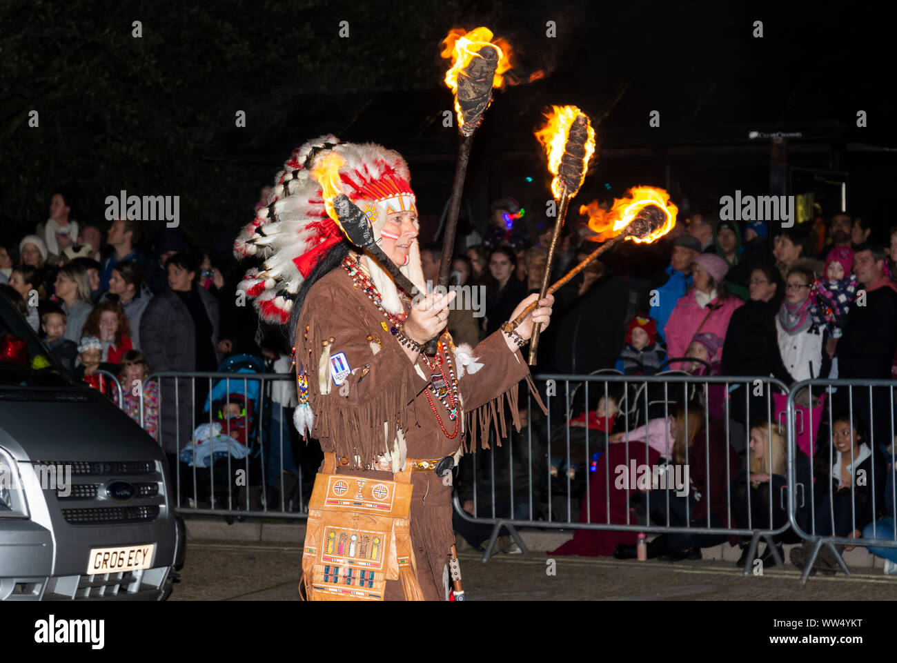 Donna vestita in rosso indiano con fiaccole di fuoco prendendo parte a una processione mentre a Guy Fawkes evento in Littlehampton, West Sussex, Regno Unito. Foto Stock