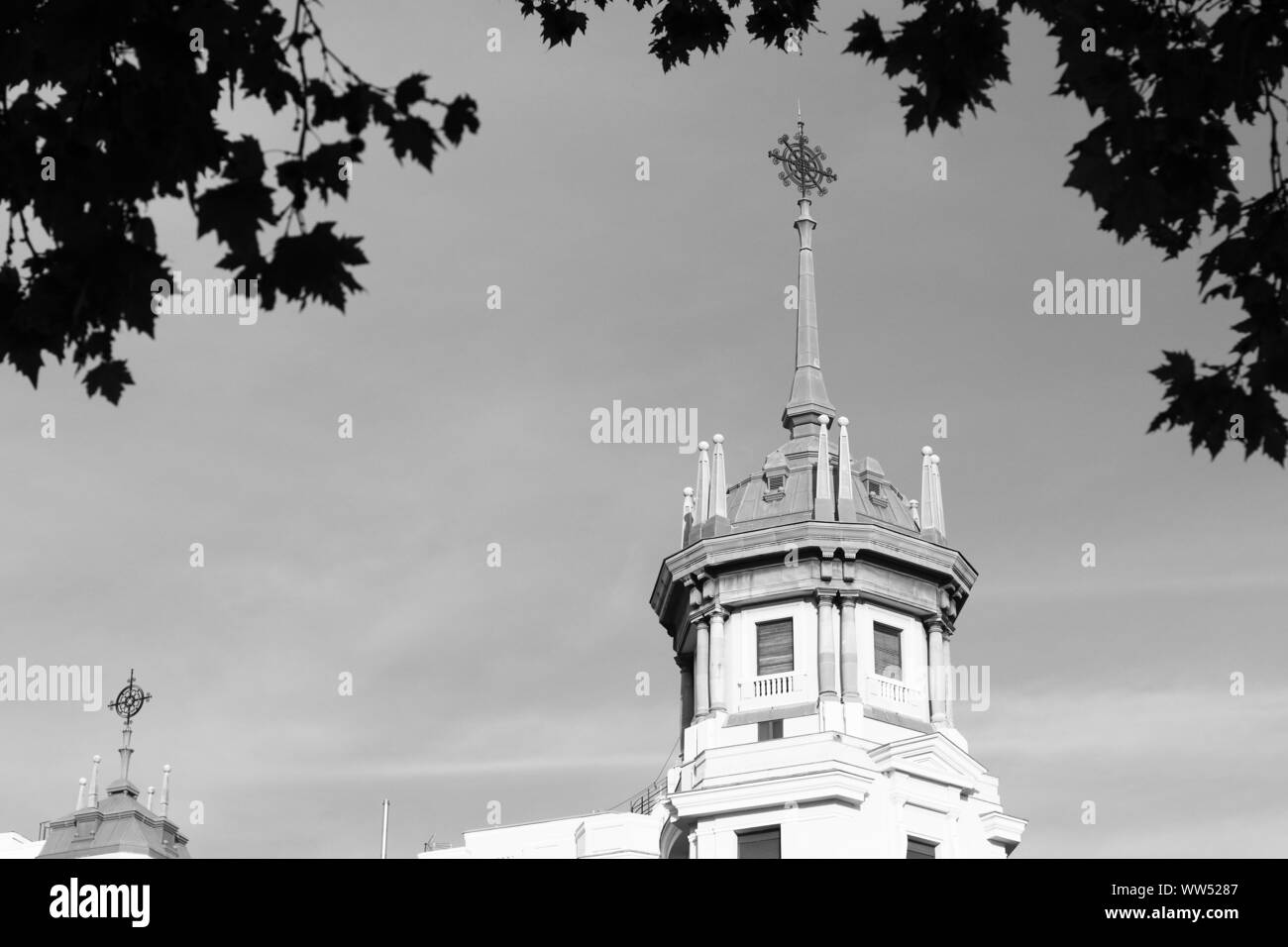 Si tratta di un vecchio edificio con torre a Madrid che incorniciato da foglie Foto Stock