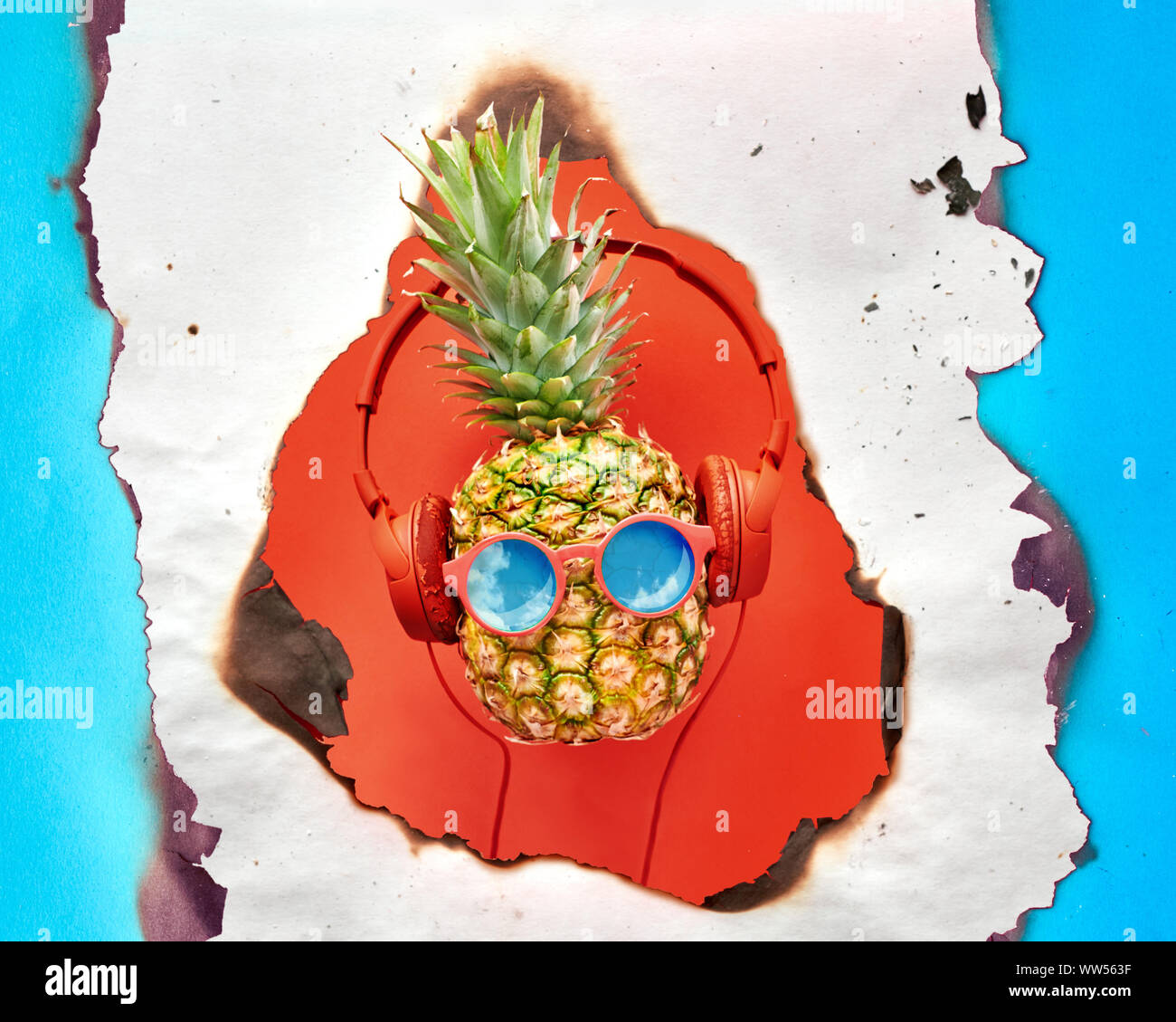 Funny ananas blu dipinta in rosso in occhiali da sole e auricolari. Appartamento laici corallo su carta a colori con cerchi. Foto Stock
