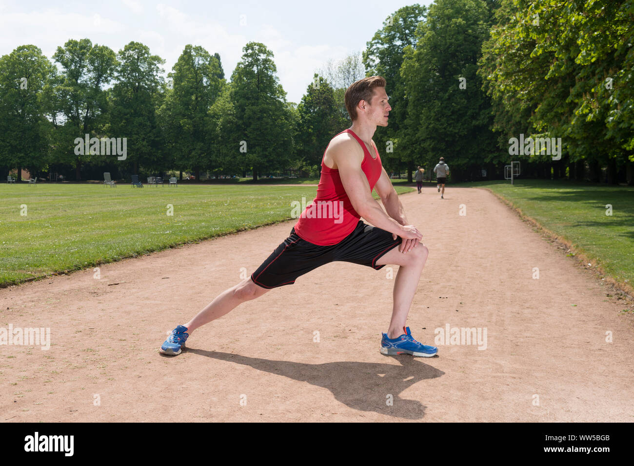 Uomo in abbigliamento sportivo stretching, vista laterale Foto Stock