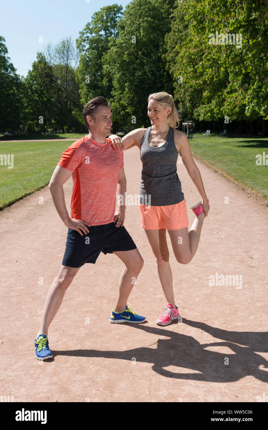 Matura in sportswear sulla via del parco, stretching esercizio, stretching Foto Stock