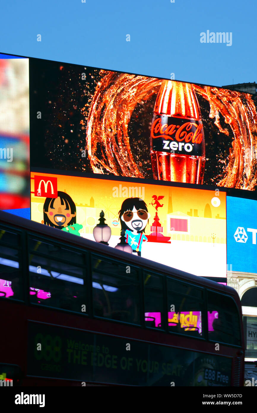 Un rosso double-decker bus passato alla guida di una grande scatola di annuncio sulla Piccadilly Circus a Londra, Foto Stock
