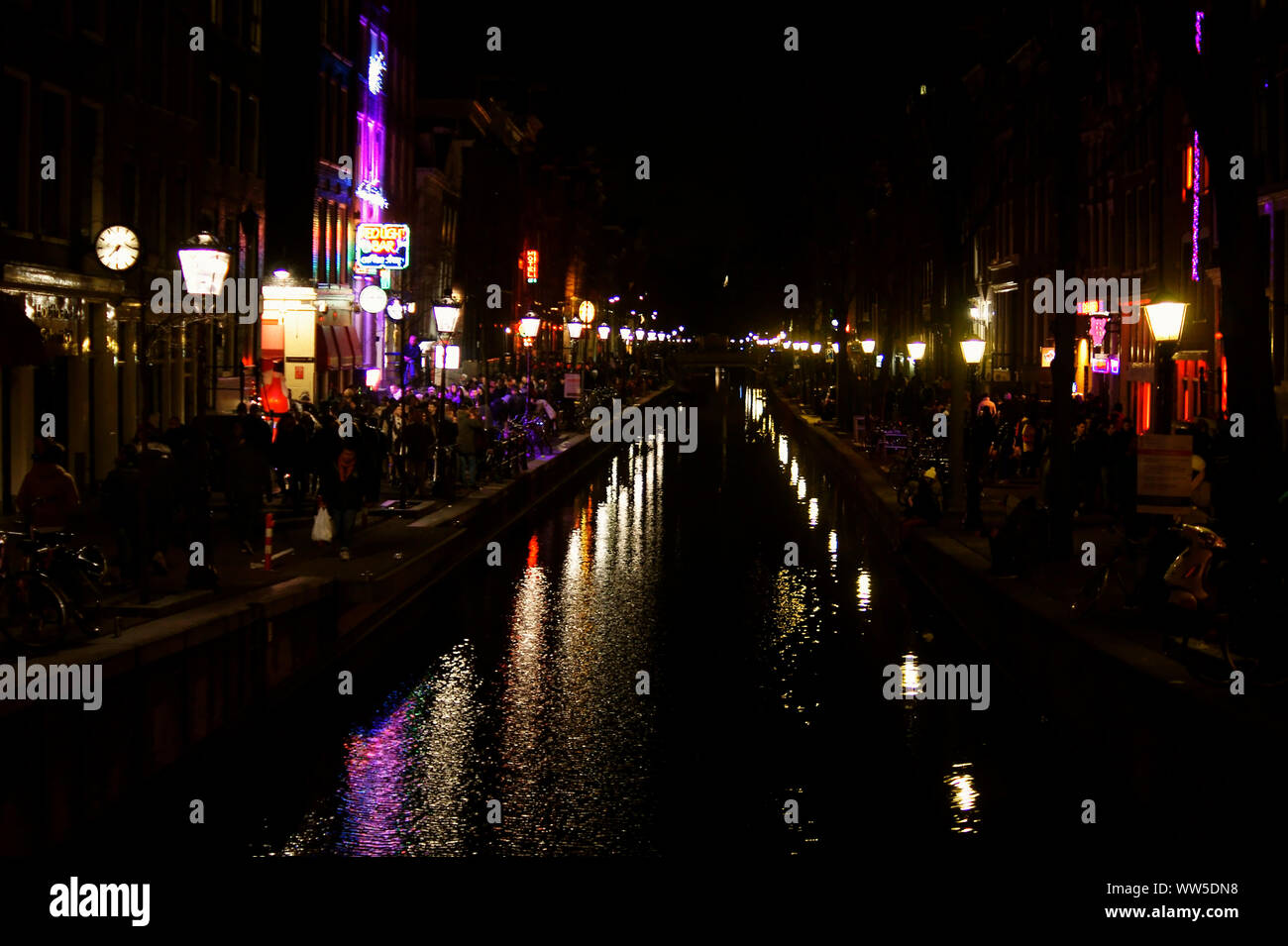 I turisti, lanterne rosse e le luci al neon si riflettono sulla superficie di un canale nel quartiere a luci rosse di Amsterdam, Foto Stock