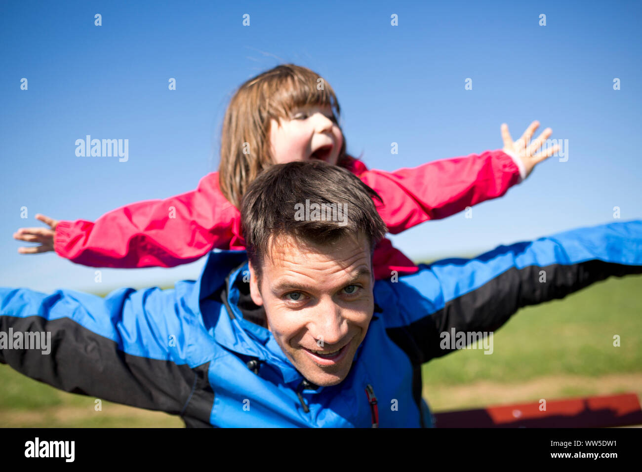 Padre con la figlia sul retro, riproduzione di aeroplano Foto Stock