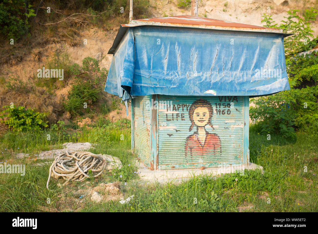 Dipinto di stagno shack coperta con un foglio di alluminio accanto a fune sul prato verde Foto Stock