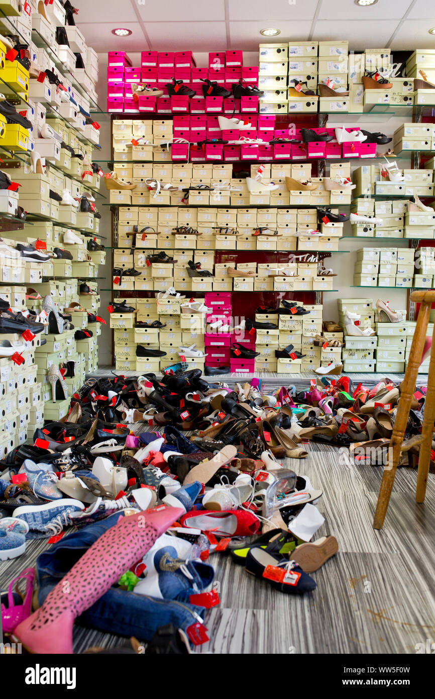 Negozio con le scatole di scarpe in scaffale e di molte scarpe sul pavimento Foto Stock