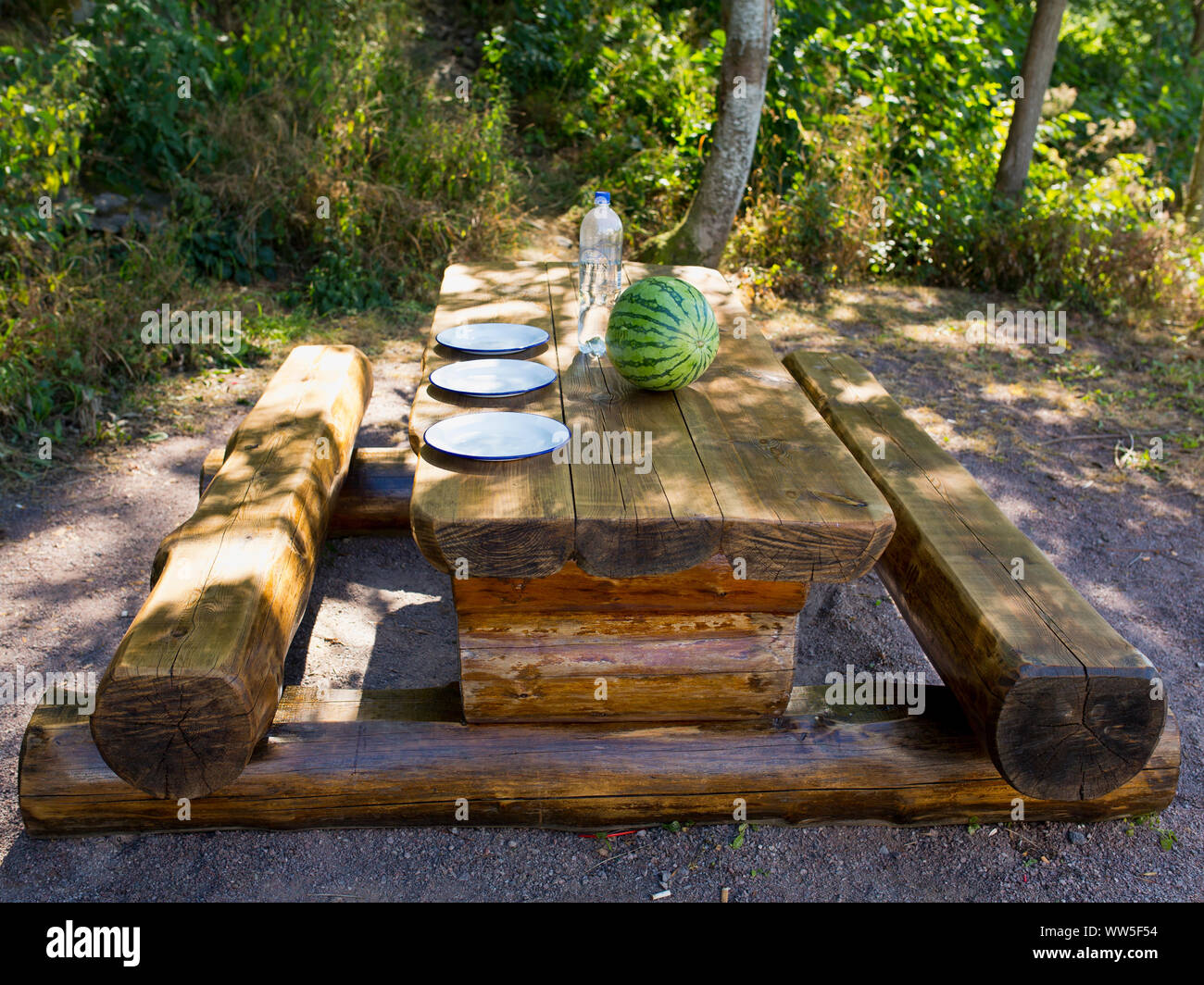 Di cui tavolo in legno con panca in legno con tre piastre e un melone verde Foto Stock