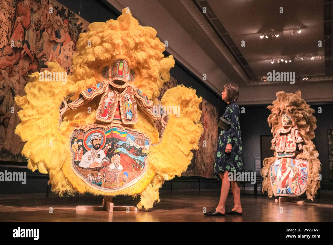 Londra, UK, 13 settembre 2019. Un assistente pone con il colorato "mascheramento nero cultura' artista ed educatore Big Chief Demond Melancon del giovane Seminole cacciatori presenta enormi del Mardi Gras tute indiano. London Design Festival corre da 14-22 settembre 2019. Credito: Imageplotter/Alamy Live News Foto Stock