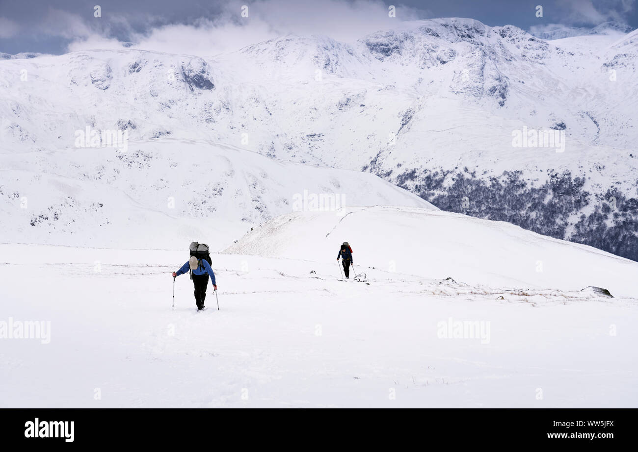 Due alpinisti Rampsgill ascendente in testa la neve in inverno dal vertice della Knott vicino Hartsop nel distretto del Lago Foto Stock