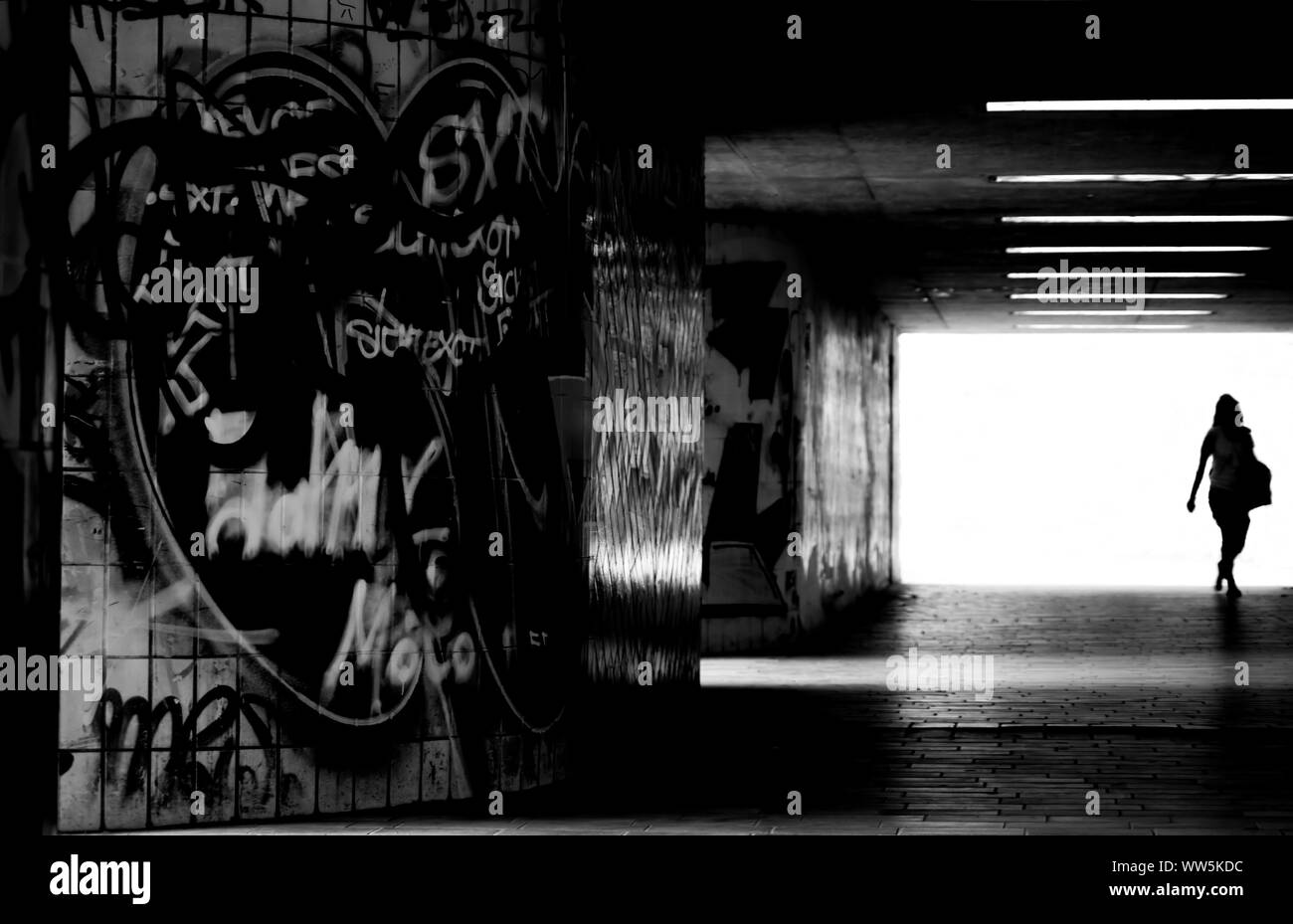 Un attraversamento pedonale un buio tunnel piastrellato con graffiti sulle pareti, Foto Stock