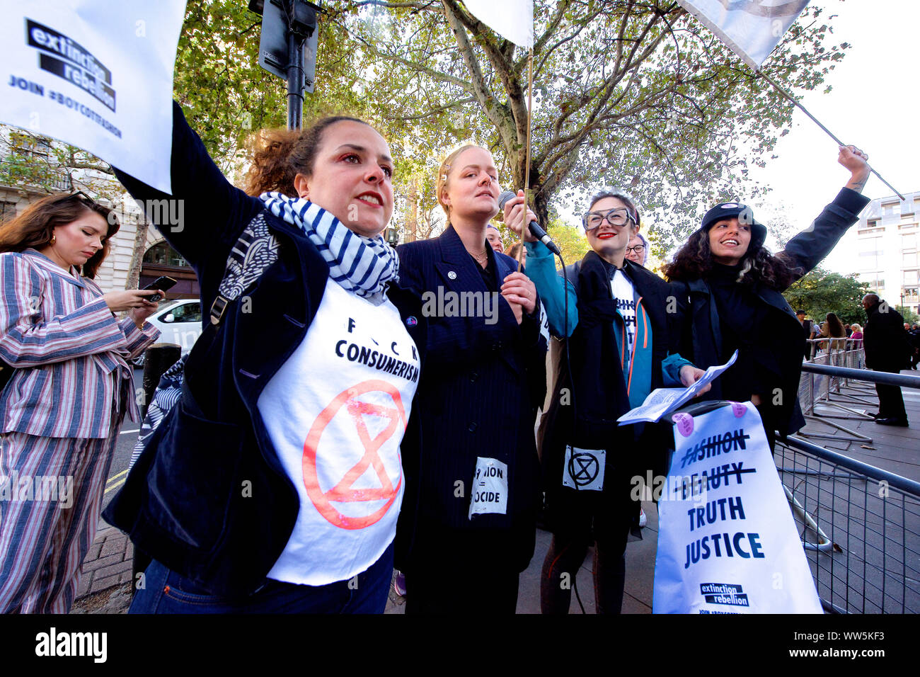 Londra, Regno Unito. Xiii Sep, 2019. Estinzione della ribellione gli attivisti in abiti bianchi e "spurgo dei cuori stessi incollato all'entrata principale del London Fashion Week la fiera. Altri membri della ribellione di estinzione versata secchi di sangue finto intorno all'entrata e condotti a 'die-NELL', chiamando per l'industria della moda di dire la verità circa il suo contributo al clima e alla crisi ecologica Credit: Gareth Morris/Alamy Live News Foto Stock