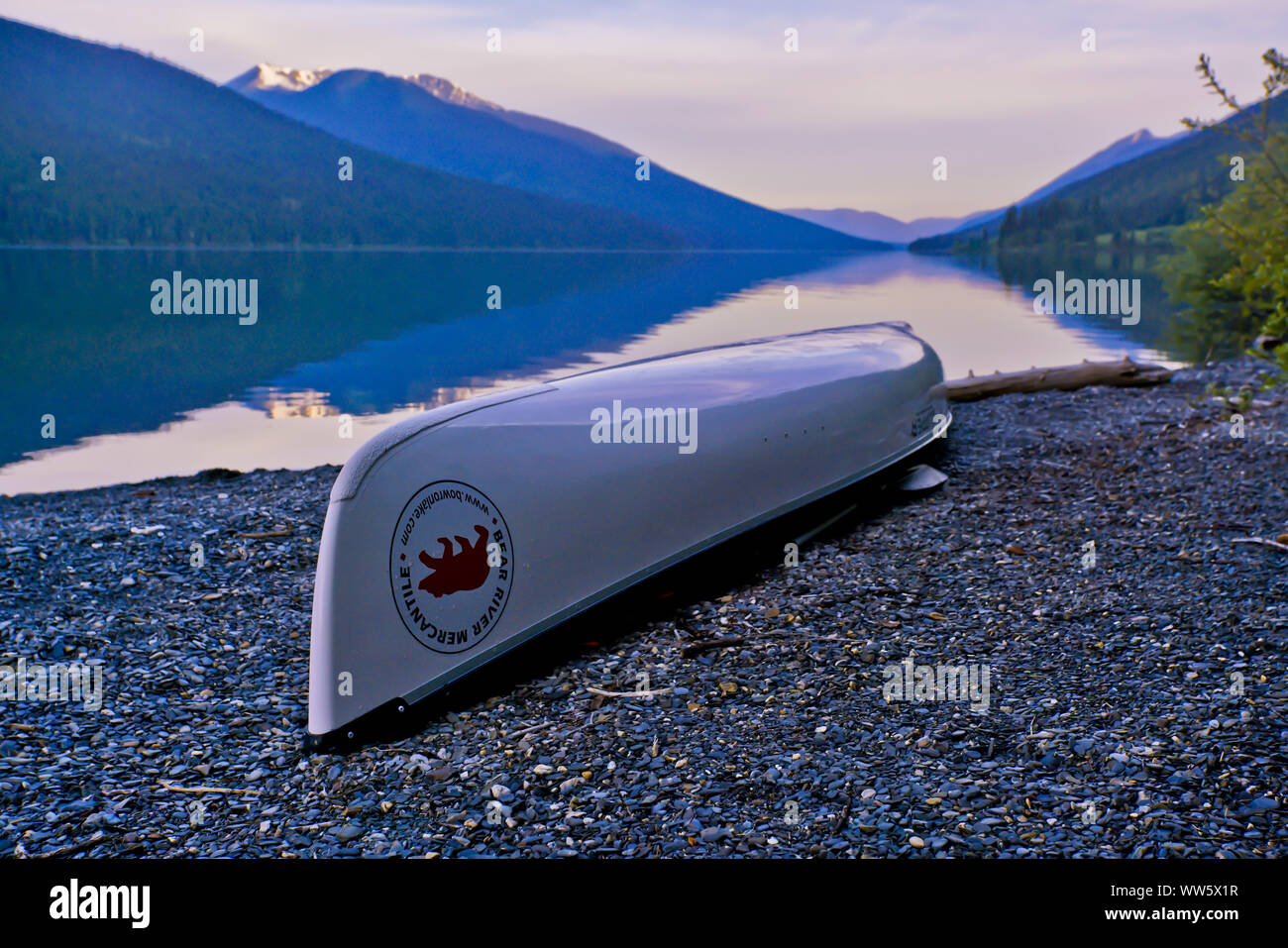 Una canoa sulla spiaggia di ghiaia, viola la luce del mattino, canoa in Bowron Lake Provincial Park, Cariboo Mountains, Canada Foto Stock