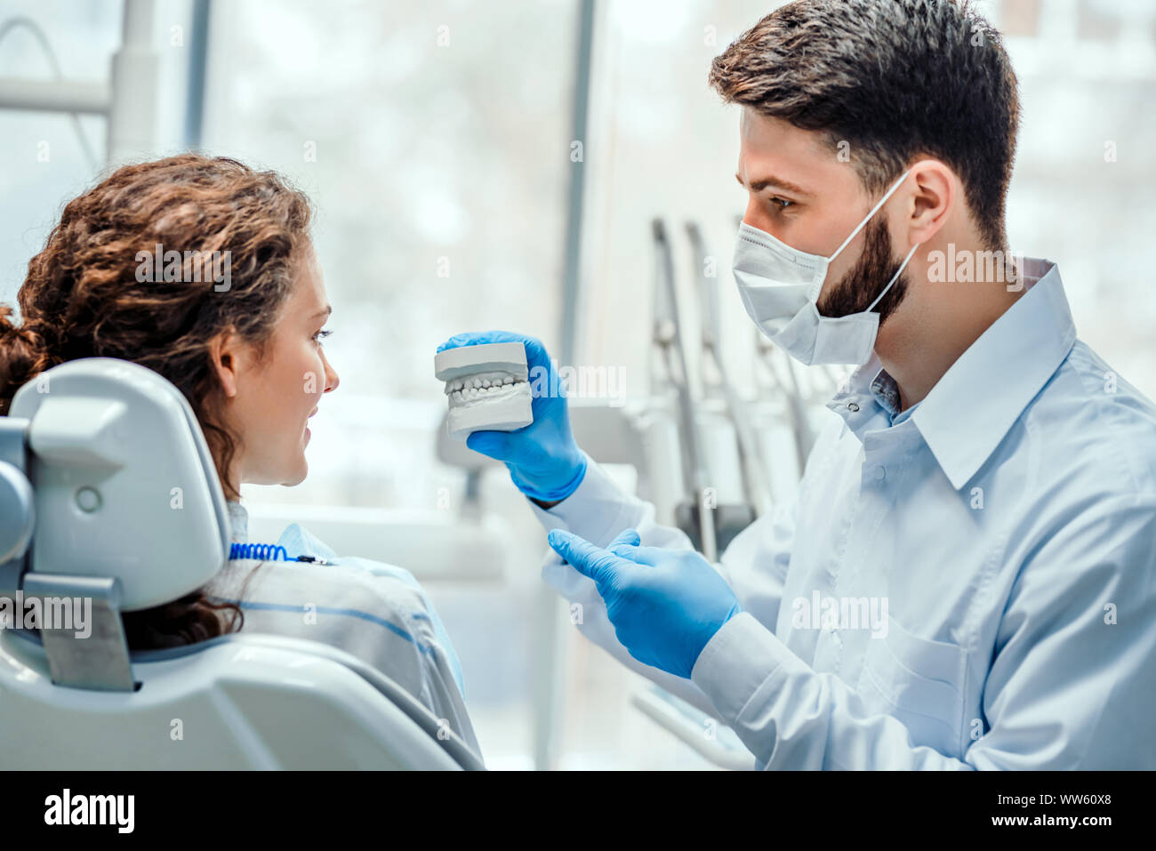 Dentista a parlare con il suo paziente mostrando il suo stampo dentale. Vista laterale. Foto Stock