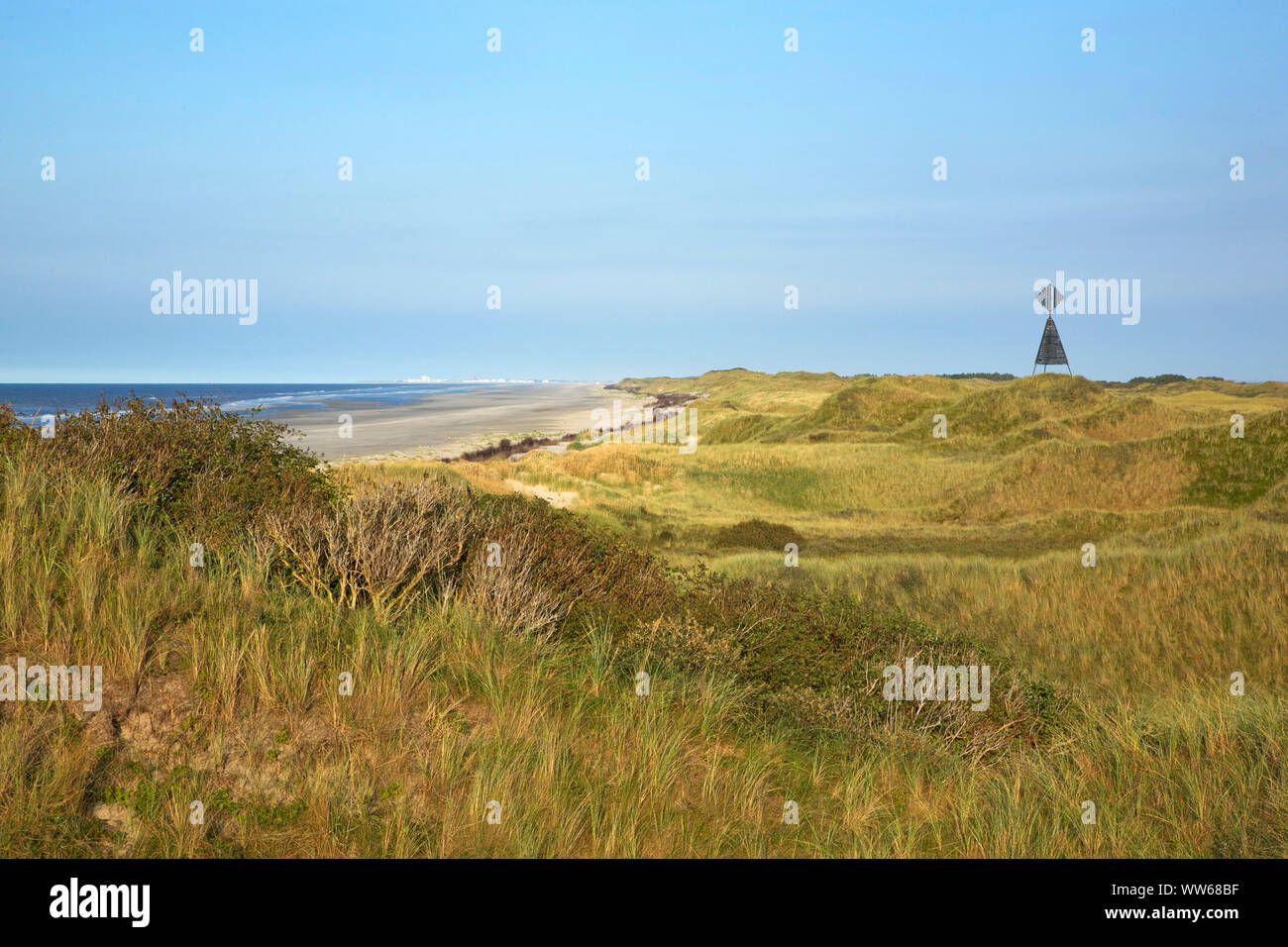 Vista del HaaksdÃ¼nen oltre il mare del nord Isola Juist. Sulla destra il west il faro a luce rotante. All'orizzonte il luogo Norderney. Foto Stock