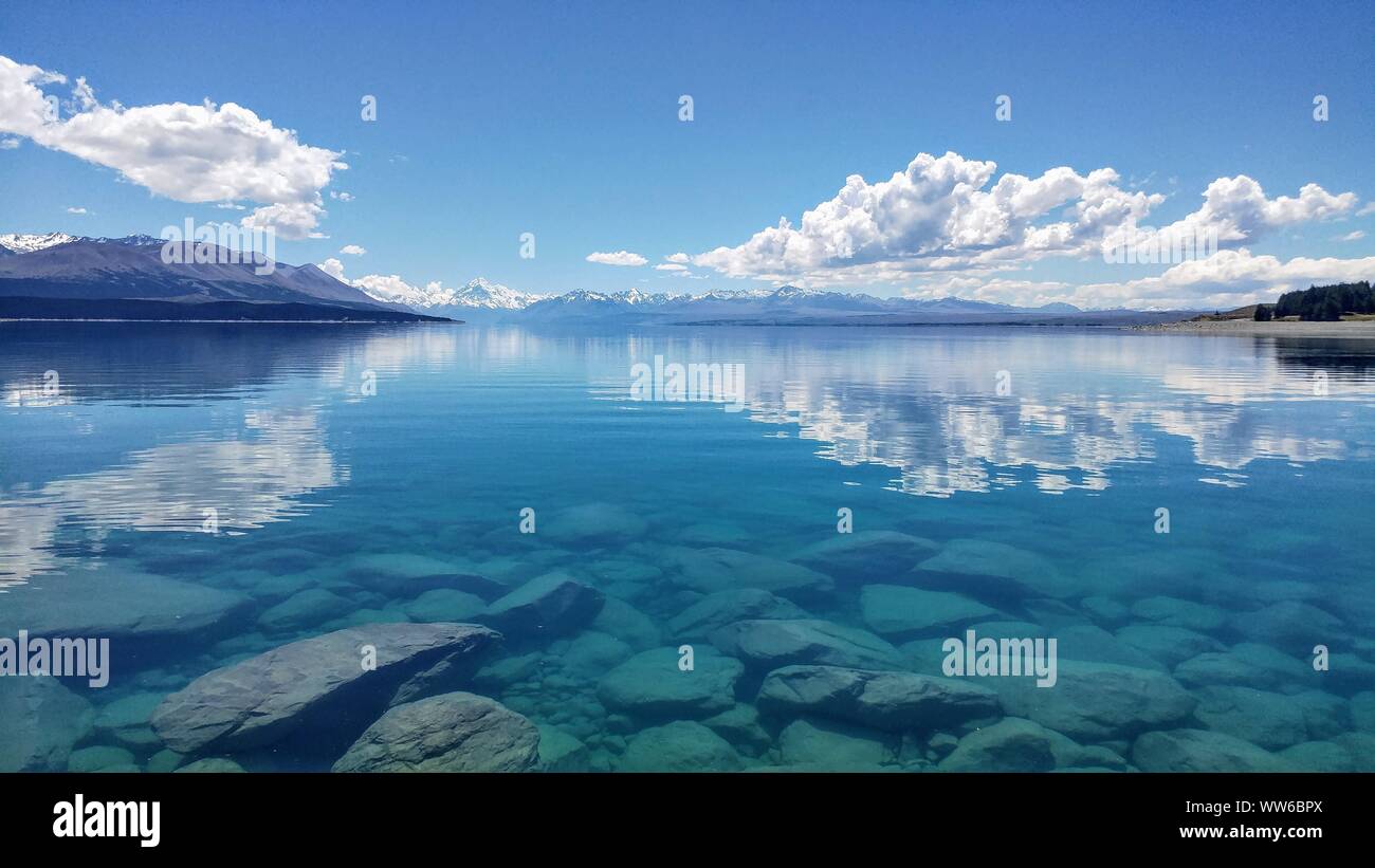 Acqua cristallina con la montagna innevata all'orizzonte, Nuova Zelanda Foto Stock