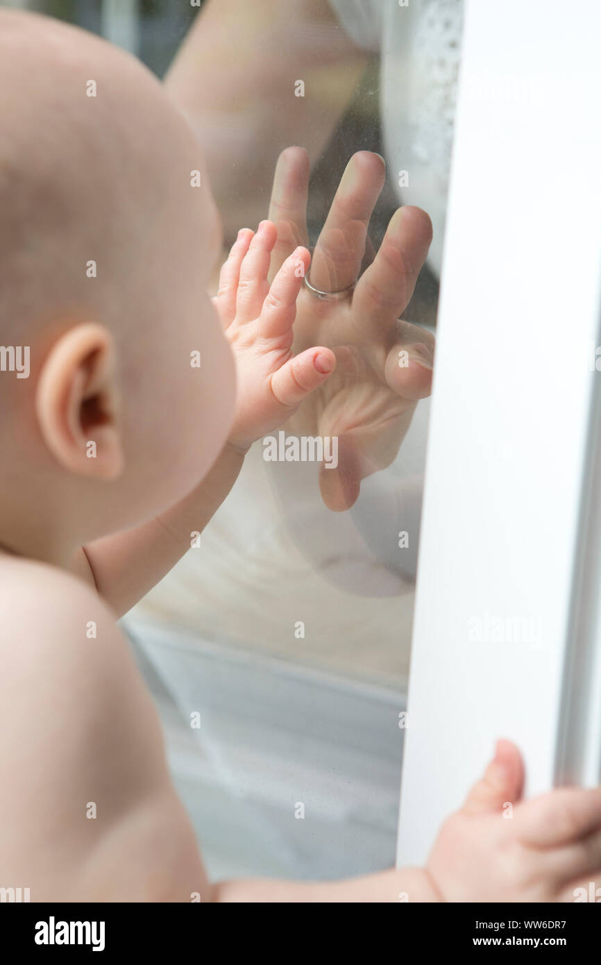 Bambino sta cercando le madri mano dietro lo schermo di vetro, ritratto Foto Stock