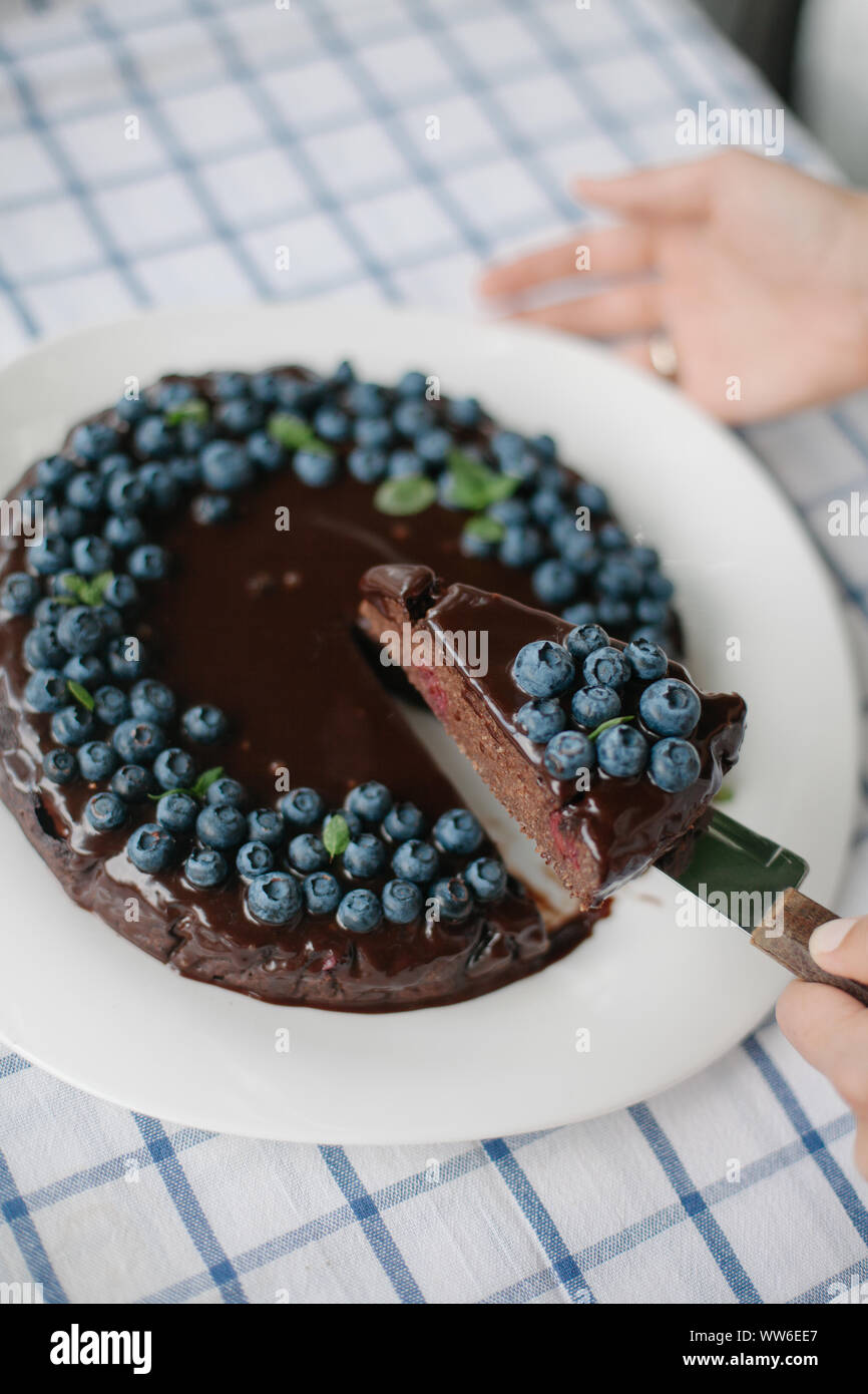 Donna che serve una fetta di mirtillo brownie al cioccolato torta Foto Stock
