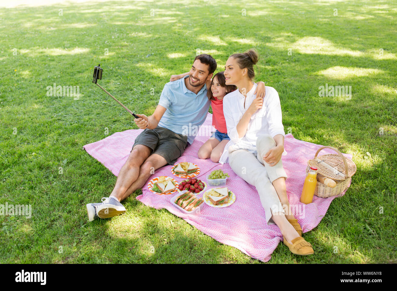 Famiglia avente un picnic e tenendo selfie presso il park Foto Stock