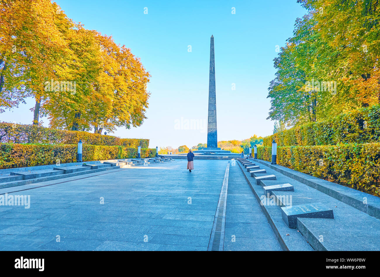 Il vicolo con il memorial piastre degli eroi della seconda guerra mondiale nel parco della gloria eterna con la pietra obelisco e la fiamma eterna a Kiev, Ucraina Foto Stock