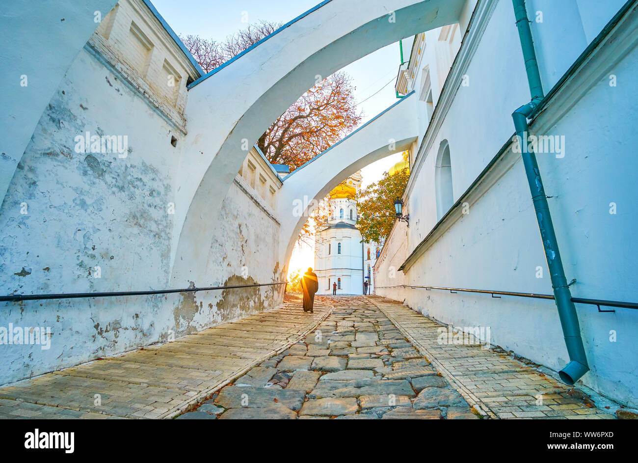 I monaci di Kiev Pechersk Lavra Cave Monastery vanno alla Cattedrale della Dormizione con una vista sul tramonto del sole e sui luminosi alberi autunnali a Kiev, Ucraina Foto Stock