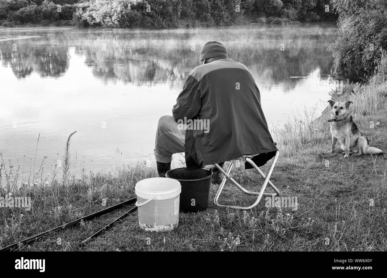 Un uomo pesca sulle rive di un bellissimo lago. Foto Stock