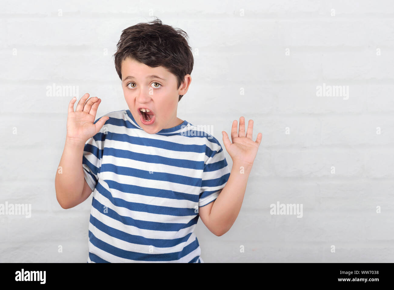 Bambino sorpreso facendo una grimace su Sfondo mattone Foto Stock