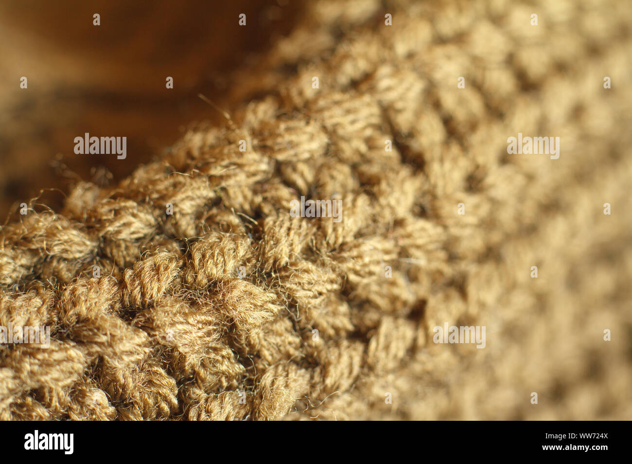 Extreme close up colore ocra naturale a maglia maglione di lana texture, pieghe ondulate, il fuoco selettivo Foto Stock