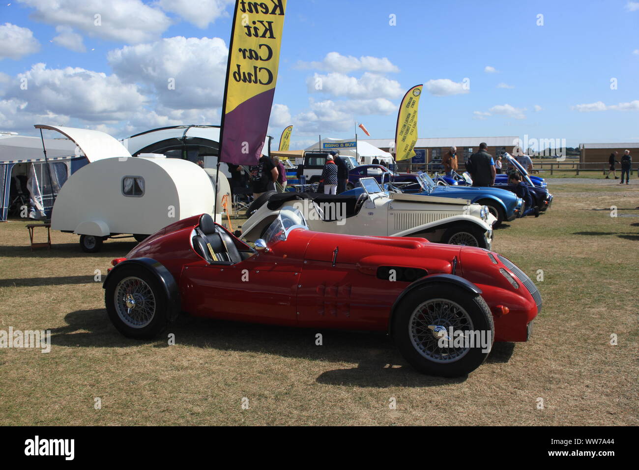 I visitatori in occasione di un evento guardando un AC Cobra Kit anglo-americano auto e altri veicoli sul display nel Kent, Regno Unito. Estate 2019. Foto Stock