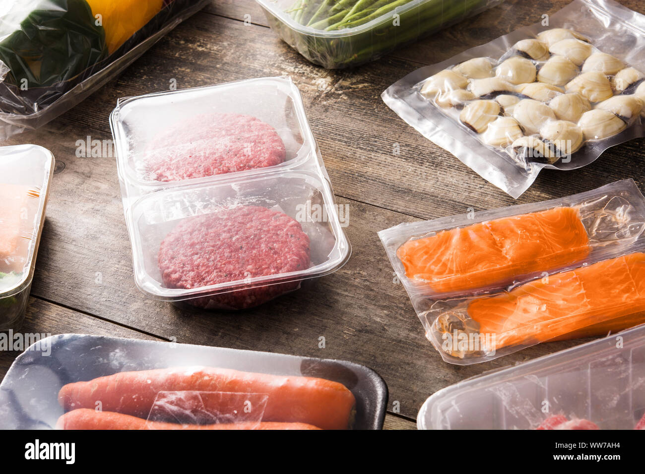 Diversi tipi di alimenti confezionati. Carne, fagiolini, carote e salmone sul tavolo di legno Foto Stock