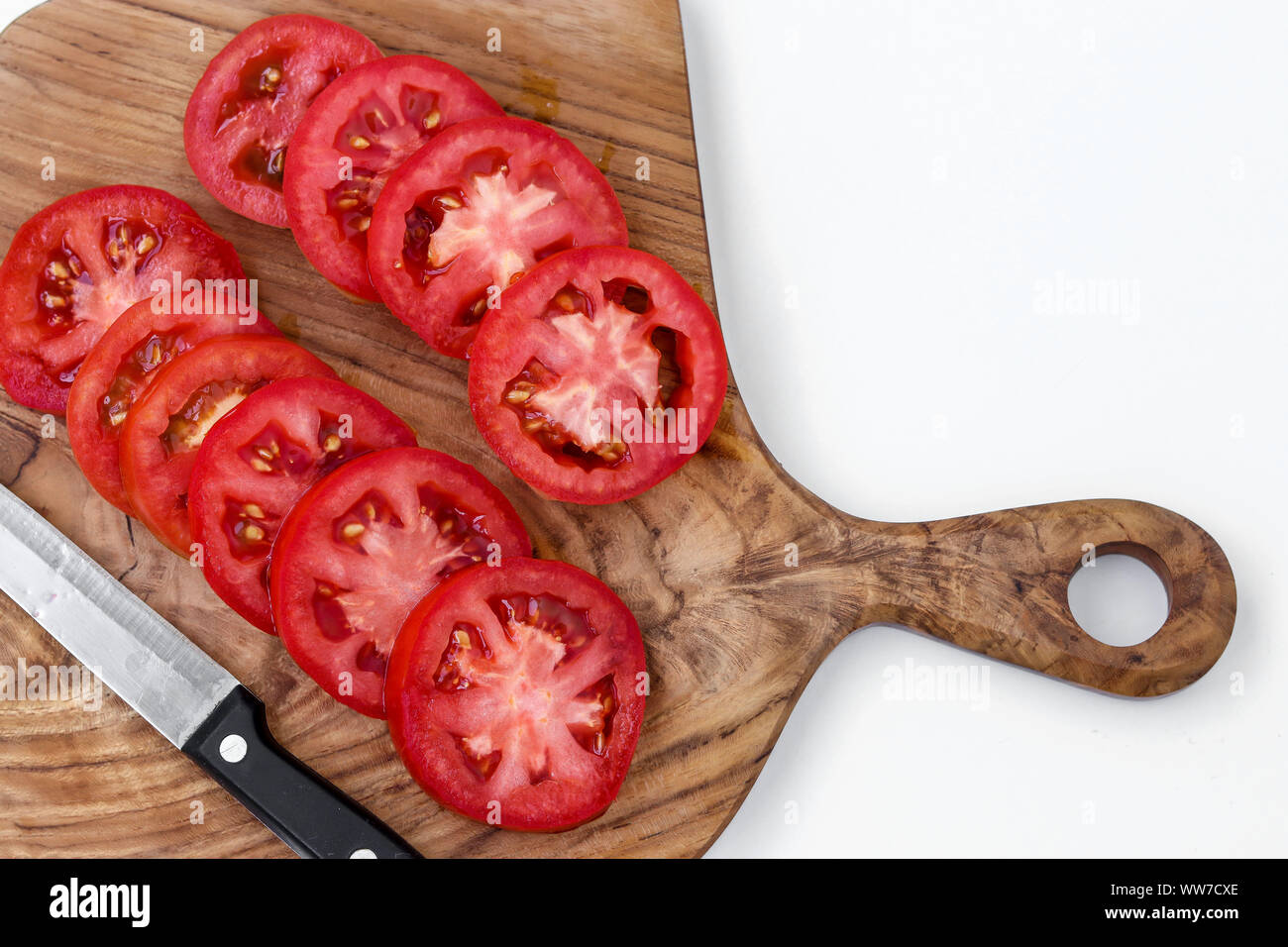 Pomodori a fettine su una tavola di legno su uno sfondo bianco, vista dall'alto, primo piano Foto Stock