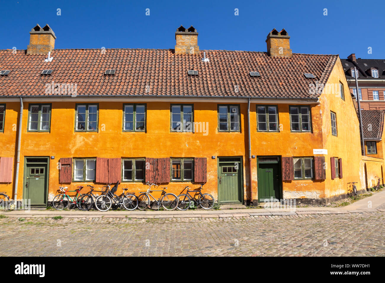 Centro storico di Riga case giallo nel quartiere Nyboder a Copenaghen, un ex quartiere navale con le bici nella parte anteriore del case Foto Stock