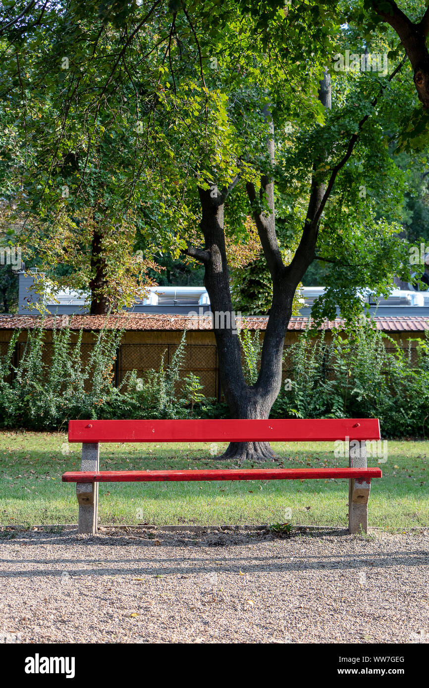 Un rosso panca di legno in un parco luci basse, grande spazio di copia Foto Stock