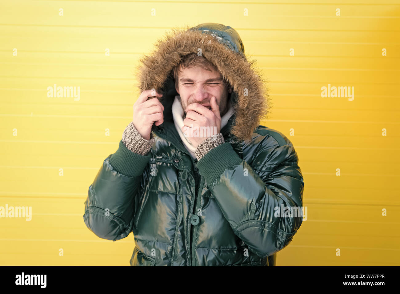 Non riesco a smettere di starnuti. Uomo bello indossare con fodera in pelliccia sintetica cofano. Modello di moda godendo di calore e comfort. Moda uomo in tempo freddo stile. Fashi Casual Foto Stock