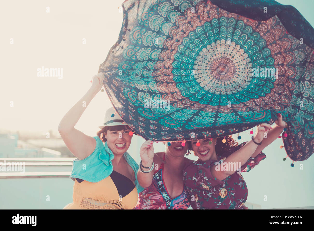 Tre giovani belle donne femmina prendere un mandala textile sopra le teste. giocando con il vento in attività outdoor. estate concetto con retroilluminazione di Sun Foto Stock