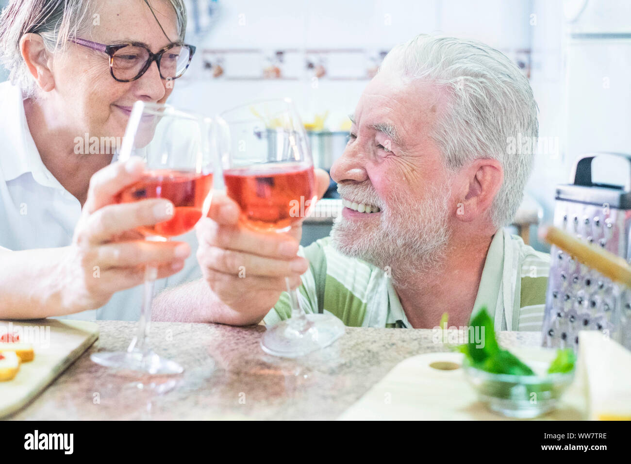 Due età adulti drinkk vino insieme in cucina a casa con sorrisi e felicità per l'amore eterno. guarda a se stessi Foto Stock