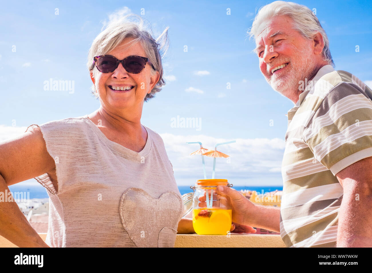 Coppia di anziani di età compresa tra bere succo di frutta sulla terrazza sul tetto con splendida vista sull'oceano. vacanza e concetto in pensione Foto Stock
