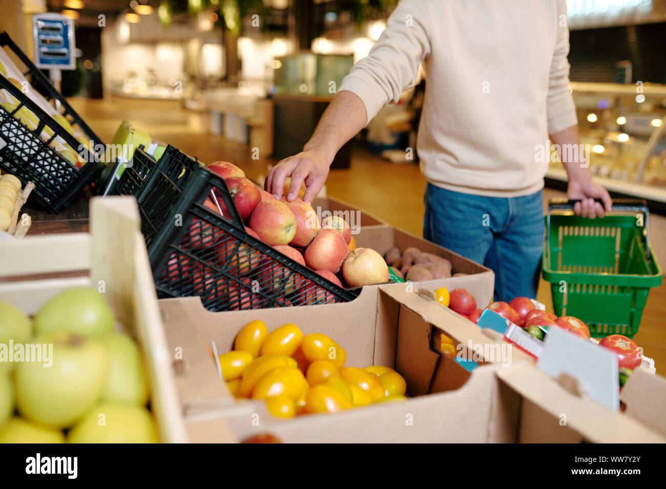 Giovane uomo informale tenendo apple dalla scatola di legno mentre visitano il supermercato Foto Stock