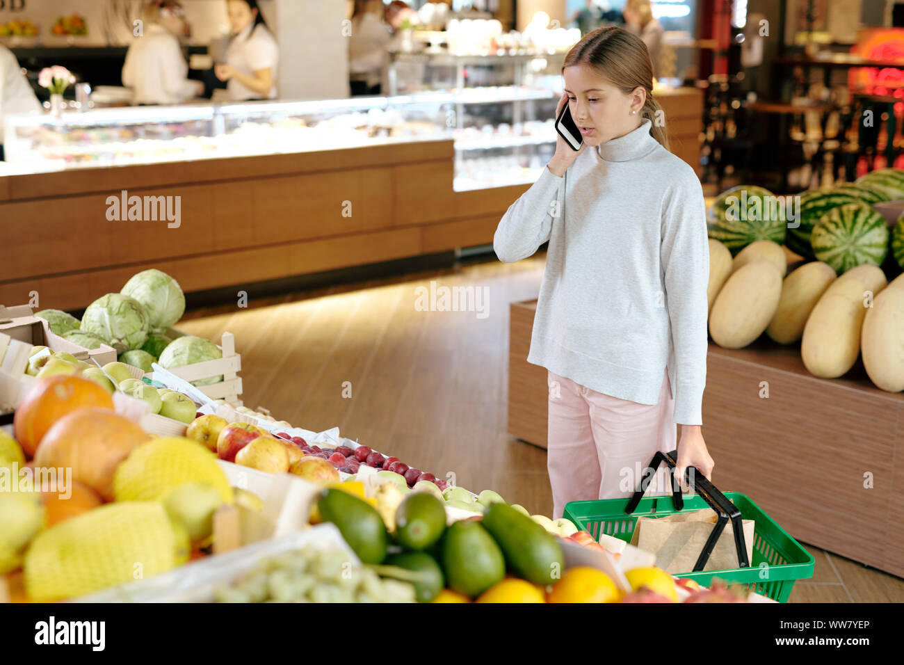 Pretty girl in informale a parlare con la sua mamma sul telefono cellulare dal display di frutta Foto Stock