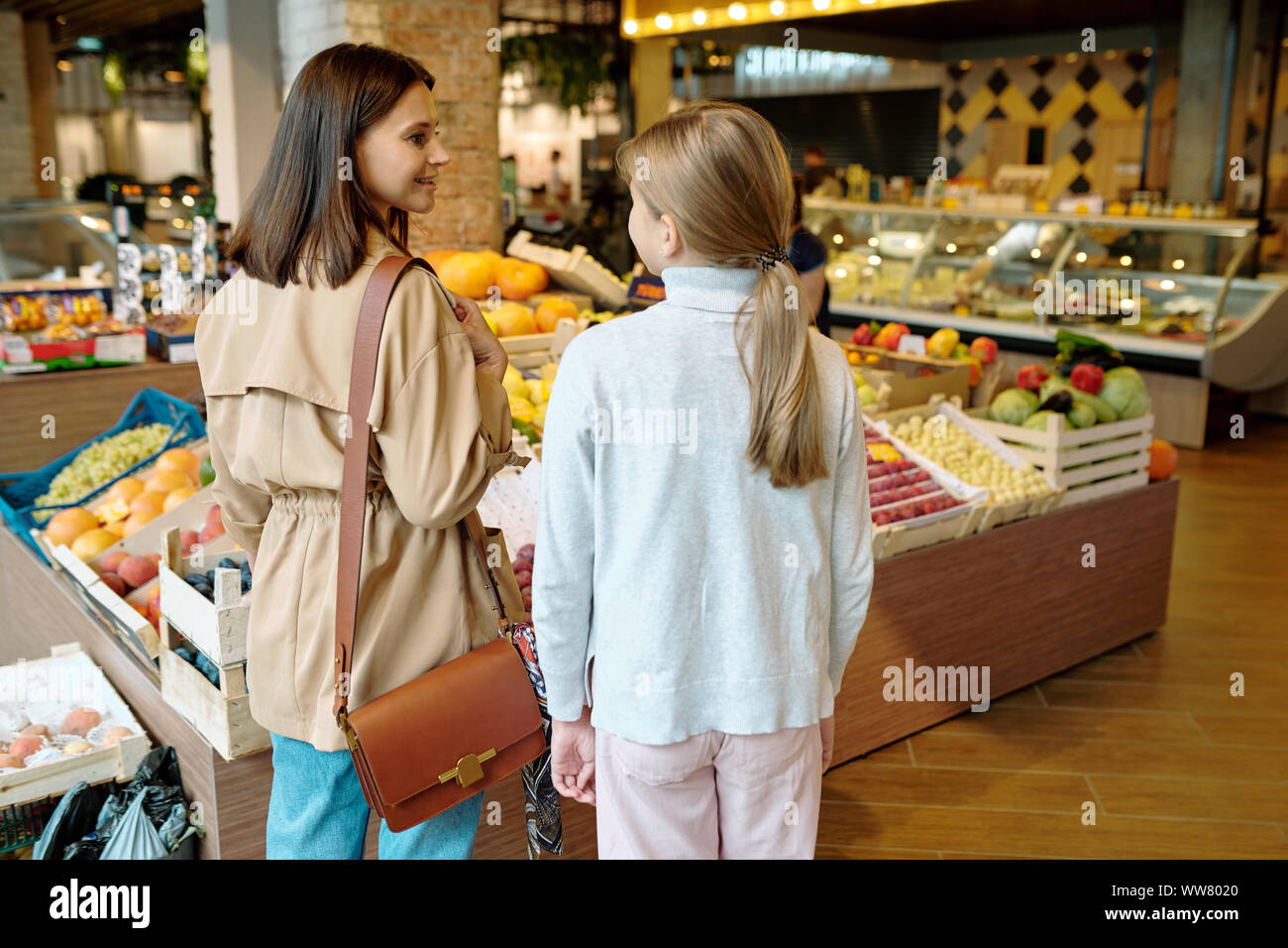 Vista posteriore del giovane ragazza e sua madre per decidere cosa acquistare nel supermercato Foto Stock