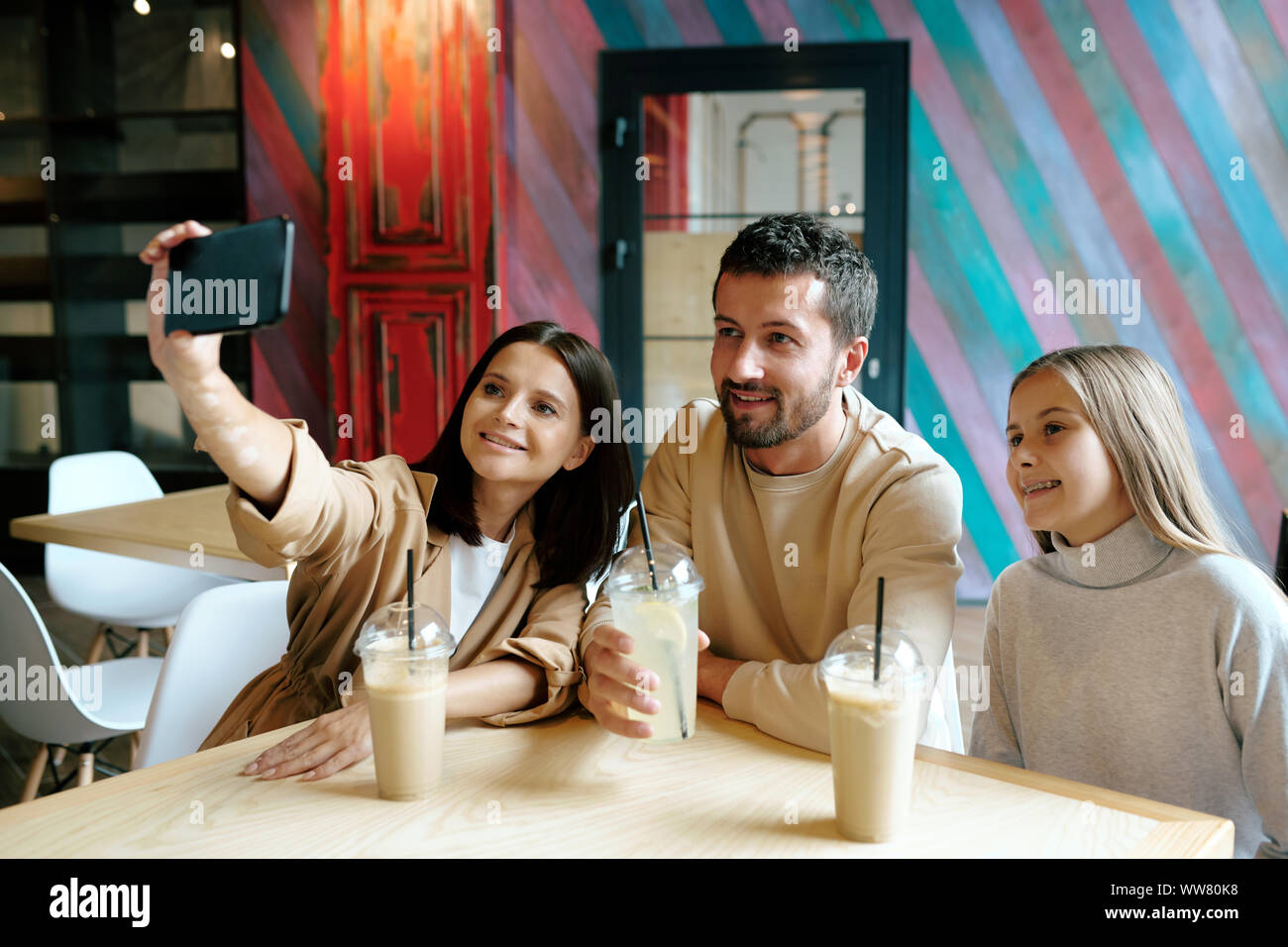 Giovane famiglia allegra di tre appoggiata dalla tabella in cafe dopo lo shopping Foto Stock